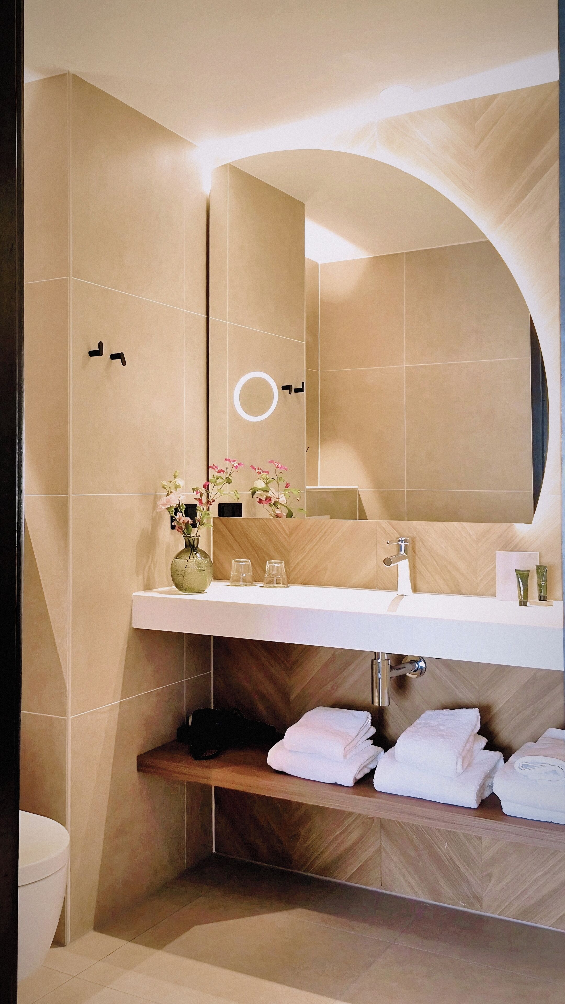 A modern bathroom with a large mirror, a sink, and a shower area.