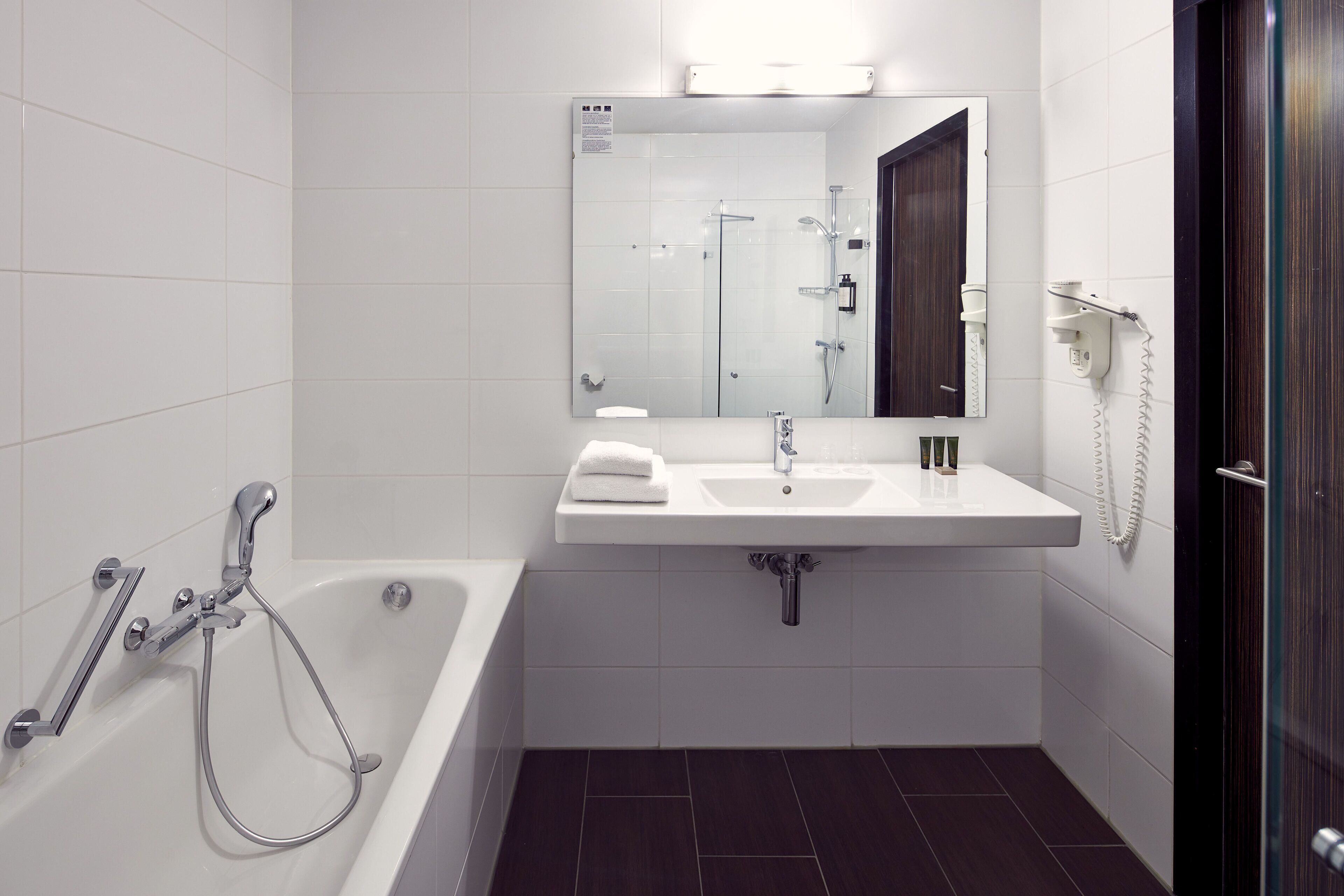 A modern bathroom with a bathtub, a sink, and a mirror.