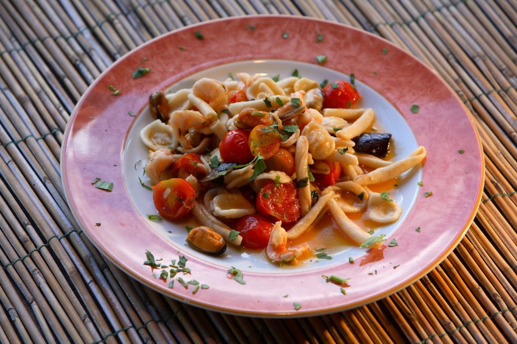 A plate of pasta with cherry tomatoes and herbs.