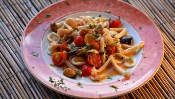 A plate of pasta with cherry tomatoes and herbs.