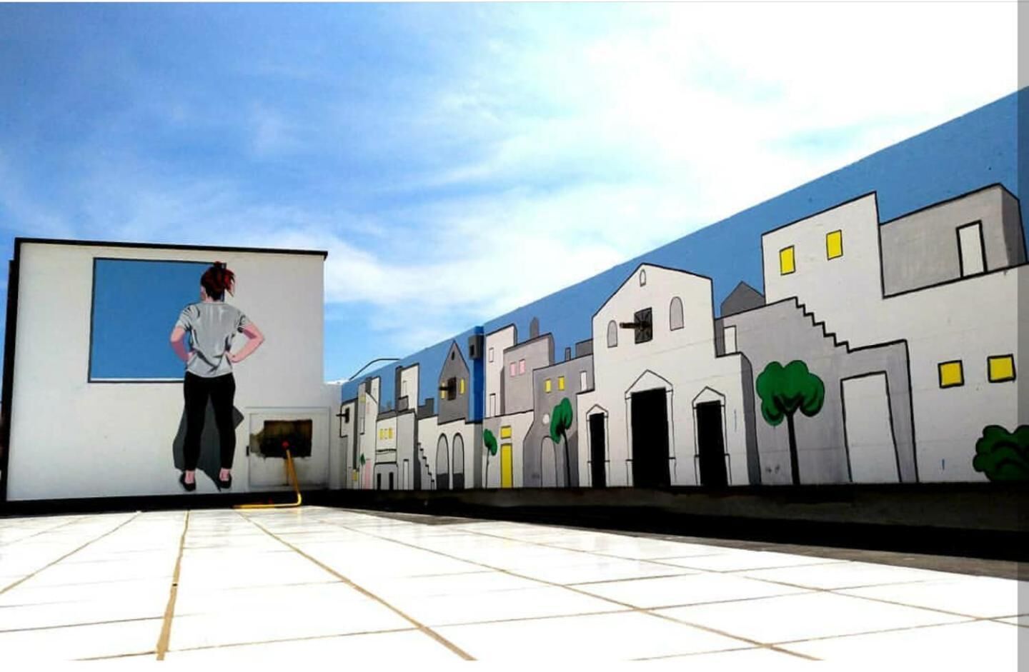 Una persona de pie frente a una gran pantalla con un mural de un paisaje urbano.