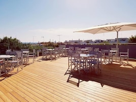 Una terraza de madera con mobiliario exterior y un paraguas grande.
