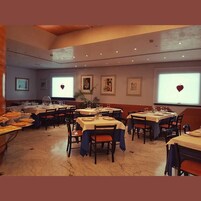 Un comedor con mesas dispuestas para comer, obras de arte en las paredes e iluminación empotrada en el techo.