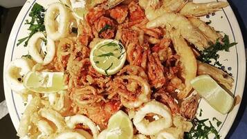 Un plato de mariscos fritos con gajos de limón y hierbas.