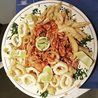 Un plato de mariscos fritos con gajos de limón y hierbas.