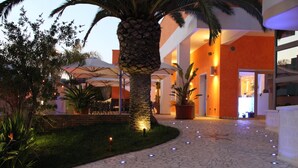Um saguão de hotel com uma palmeira, área de estar ao ar livre e piso de ladrilho de pedra.