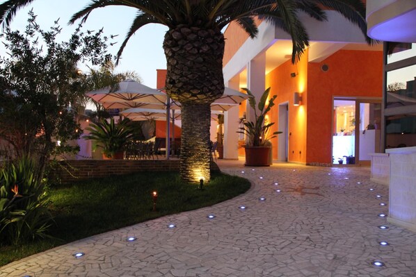A hotel lobby with a palm tree, outdoor seating, and a stone-tiled floor. - Hotel Risberg (Gallipoli)