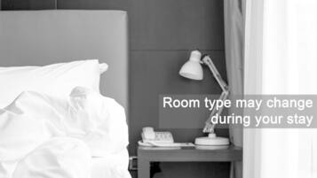 Une chambre d’hôtel avec un lit, une lampe de chevet, un téléphone et une table de chevet.