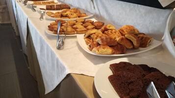 A buffet table with various baked goods including pastries and bread.