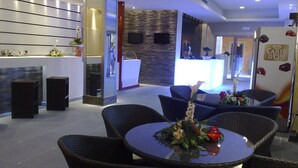 Um hall de hotel moderno com balcão de recepção, área de estar e um refrigerador decorativo.