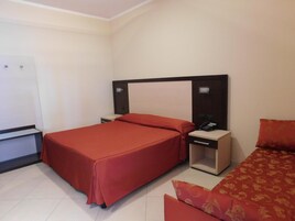 Una habitación de hotel estándar con cama, mesitas de noche, teléfono y armario.