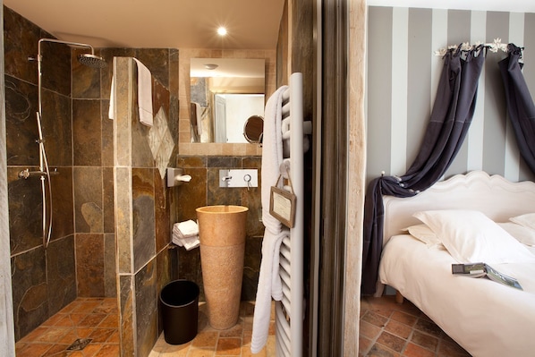 A bathroom with a shower, a large basin, and a toilet.