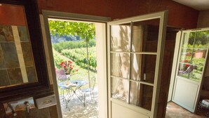 Ein Badezimmer mit einer Badewanne, einem großen Holzeimer und einer Glastür, die in einen Garten im Freien führt.