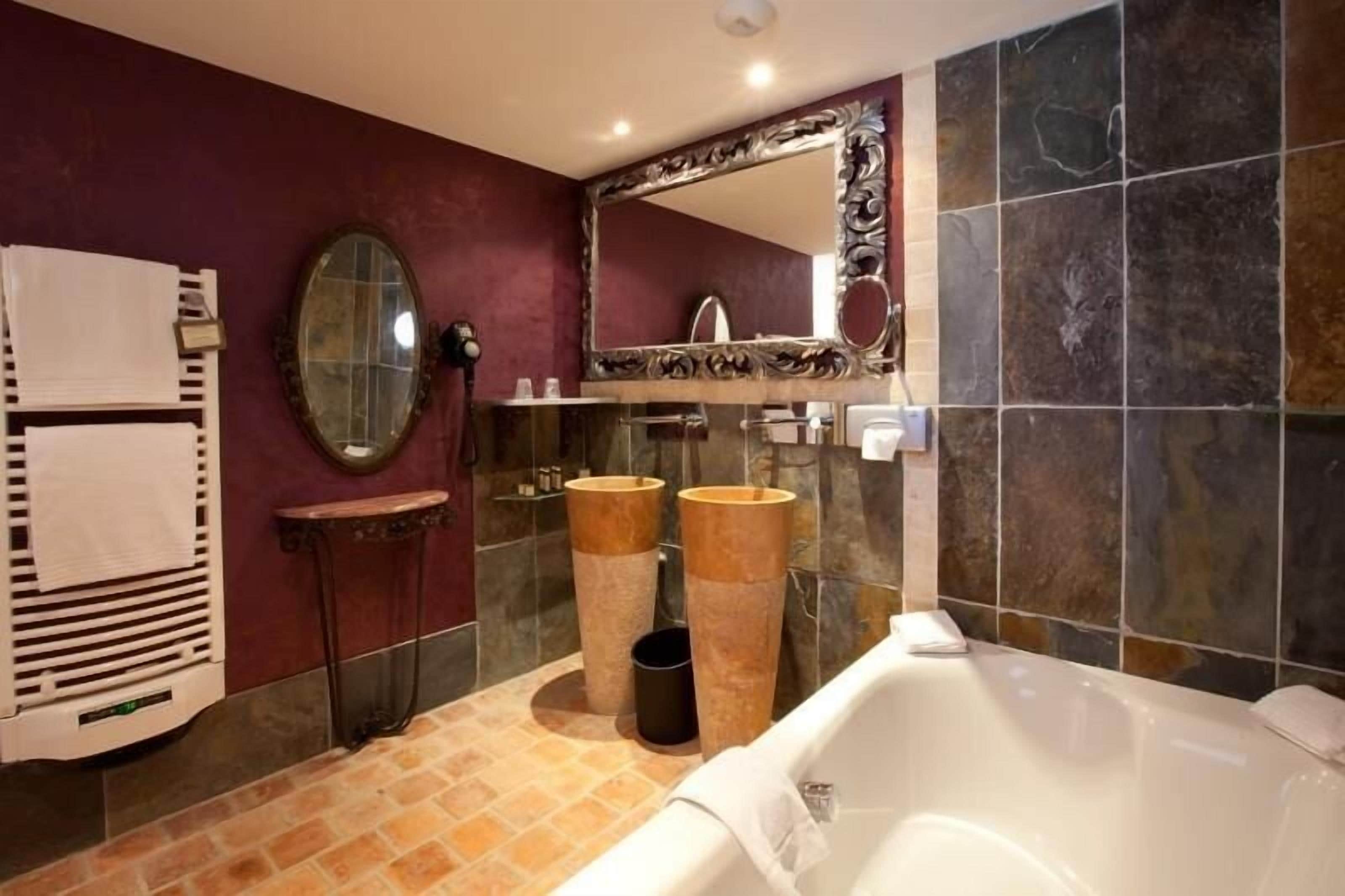 A bathroom with a bathtub, two sinks, a vanity, and a large mirror.