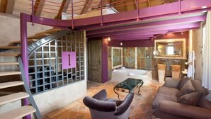 Ein geräumiger Wohnbereich mit Treppe, einer Couch, einem Couchtisch und einer Badewanne.