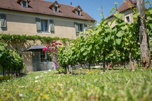 A building with a garden in front, including a pergola with flowers and a bench. - Hotel-Spa Le Saint Cirq (Tour-de-Faure)