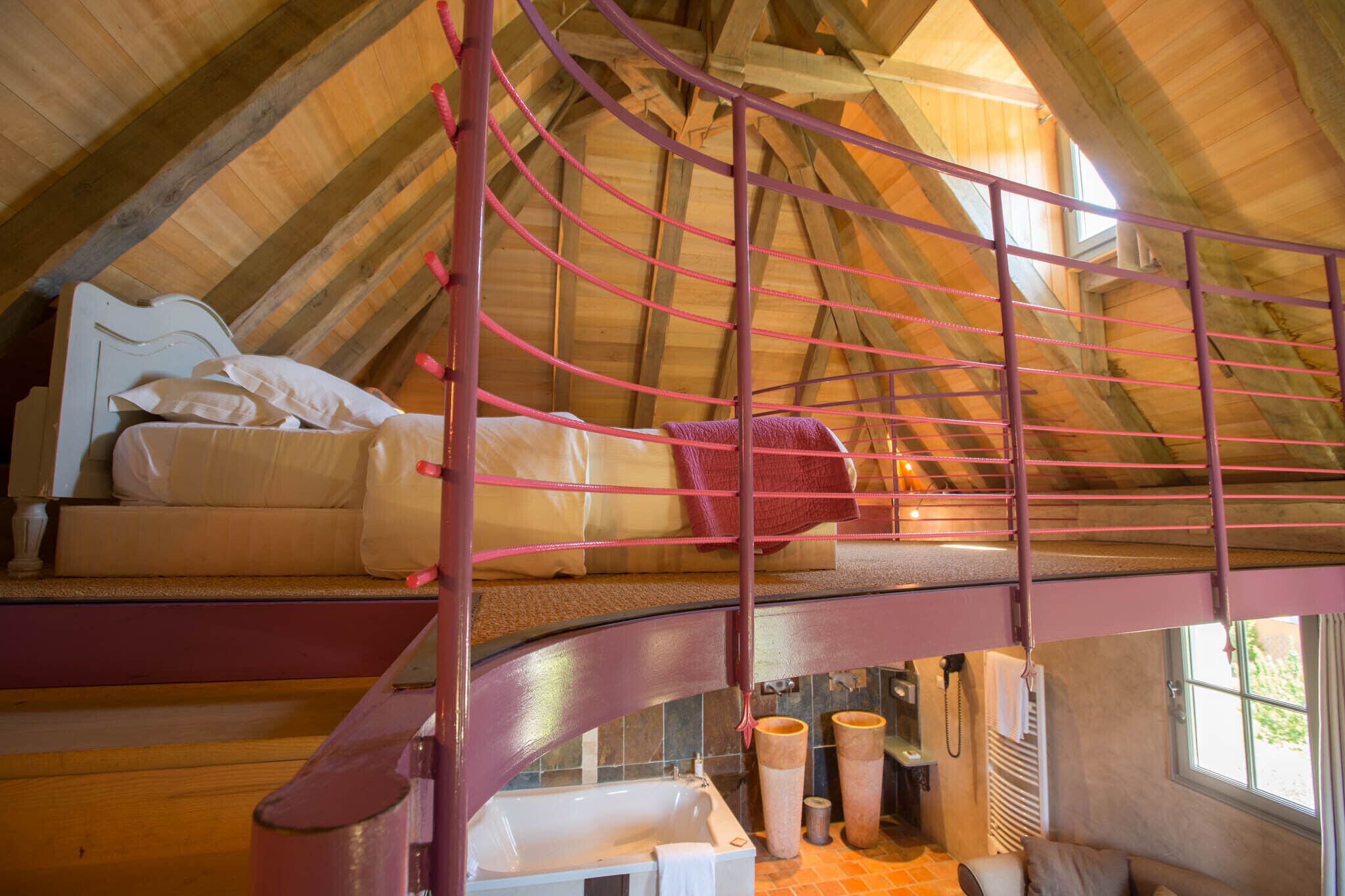 A loft bedroom with a bunk bed, a wooden ceiling, and a window.
