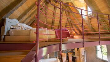 A loft bedroom with a bunk bed, a wooden ceiling, and a window.