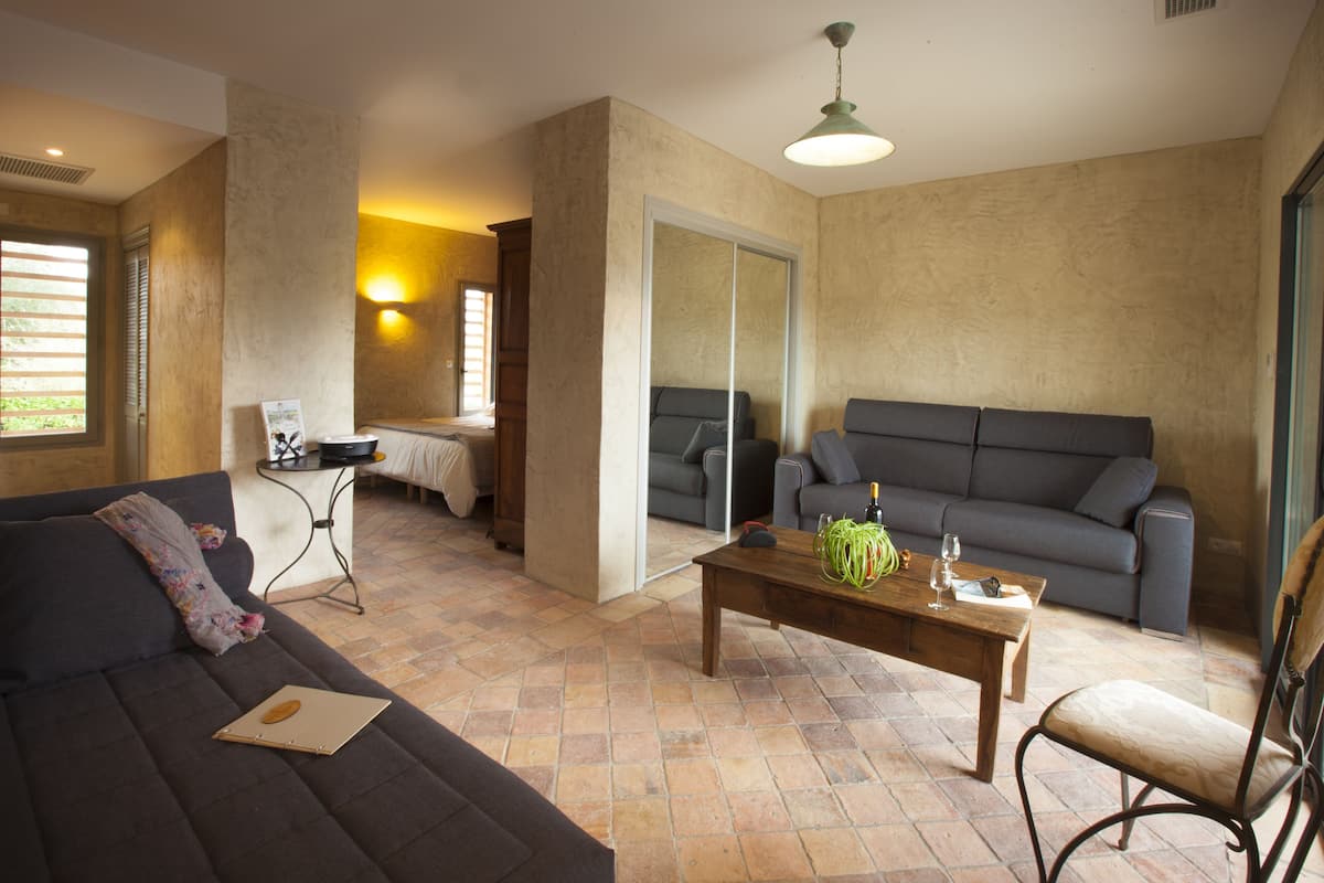 Ein Wohnzimmer mit einem dunkelgrauen Sofa, einem Holztisch und einem grauen Couchen.