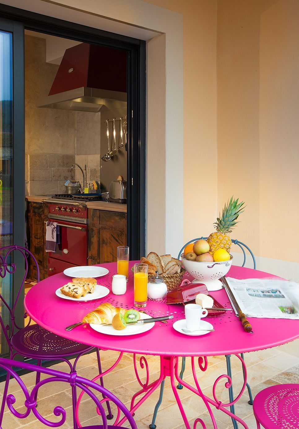 A breakfast table with plates of food, a bowl of fruit, and a newspaper.