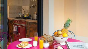 A breakfast table with plates of food, a bowl of fruit, and a newspaper.