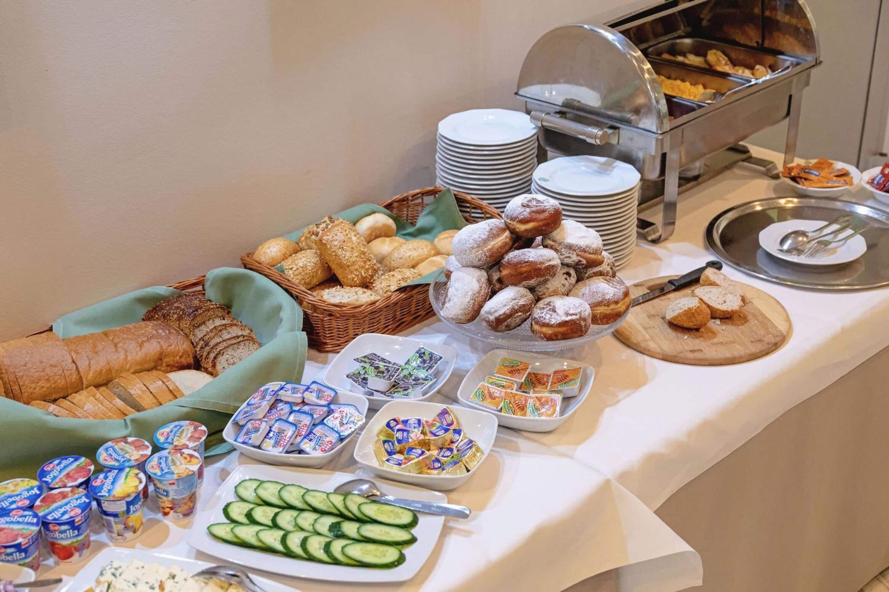 Un tavolo del buffet con diversi cibi, tra cui pane, pasticcini e latticini.