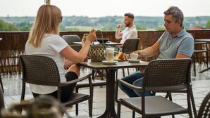 An outdoor café with tables and chairs, a view of the countryside, and umbrellas. - Hotel Gromada Lomza (Lomza)