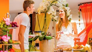 A dining area with a buffet setup, including various food items and a large vase of flowers. - Villa Baobá (Búzios)