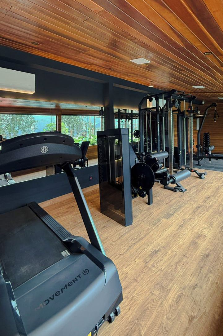 A gym with treadmills, weight machines, and a wooden floor.