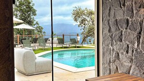 A modern interior with a stone wall, a pool, and outdoor seating. - Siramat Hotel (Petrópolis)