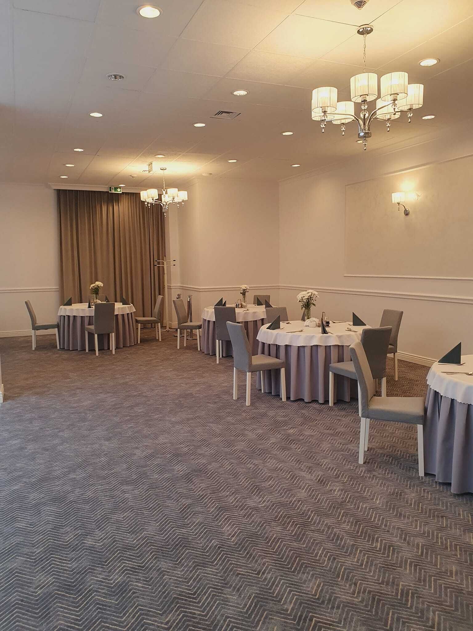 A conference room with round tables, chairs, and a carpeted floor.