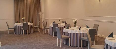 A conference room with round tables, chairs, and a carpeted floor.