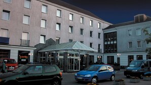 A hotel with a central entrance, multiple windows, and a parking area with cars. - Hotel Gromada Koszalin (Koszalin)