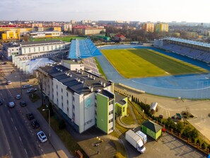 Stadium complex with a large open field and a stadium structure surrounded by various buildings.