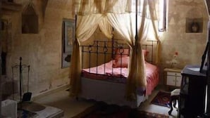 A room with a four-poster bed, a small table, and a chair. - Buyuk Sinasos Konagi (Ürgüp)