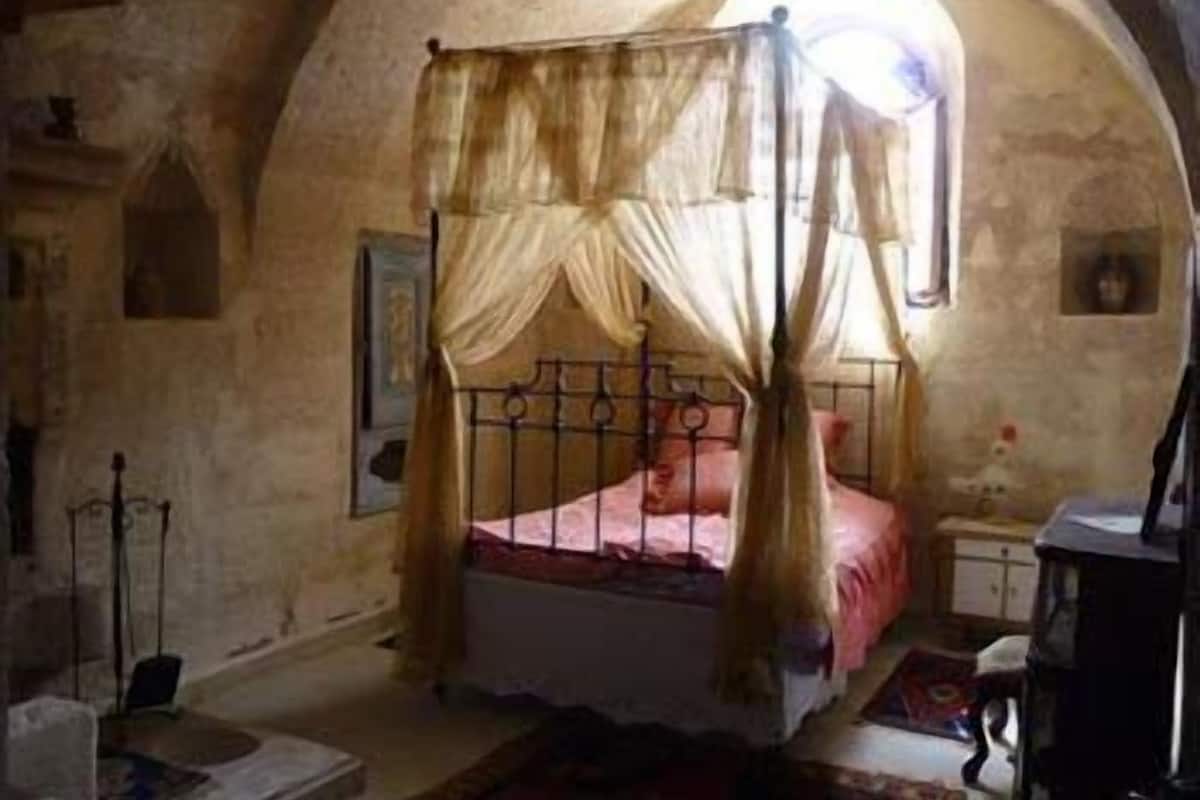 Una habitación con una cama con dosel, una mesita y una silla.