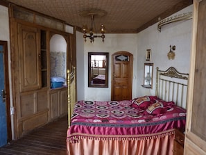 A bedroom with a bed, wooden wardrobe, and a mirror.