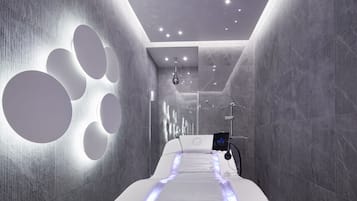 Experience a serene retreat with a long, narrow bed, wall-mounted light fixture, and spa-like shower area.