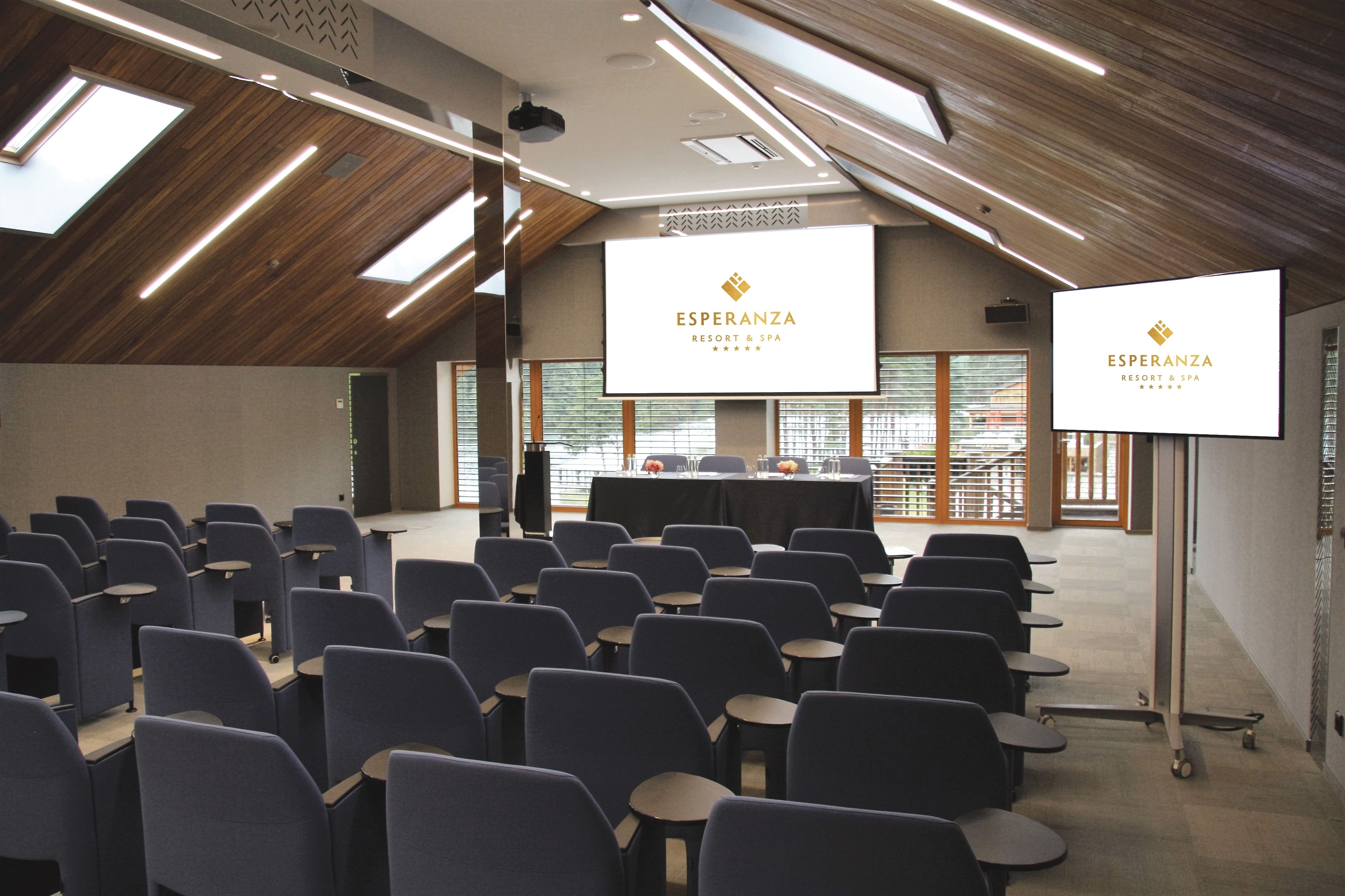 A conference room with rows of chairs, a long table, and two screens displaying the "Esperanza Resort & Spa" logo.