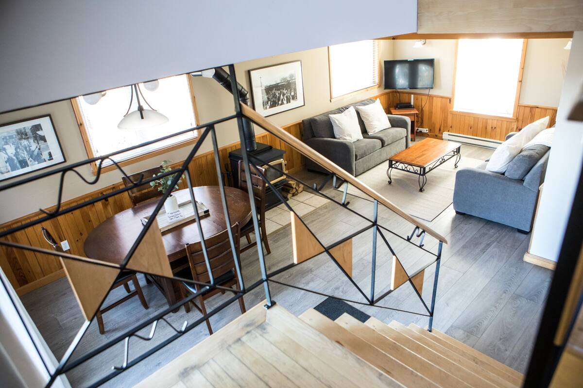Ein modernes Wohnzimmer mit Treppe, Essbereich und Fernseher.