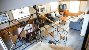 A modern living room with a staircase, a dining area, and a TV.
