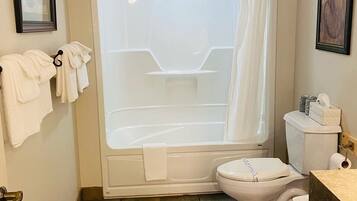 Un bagno con vasca, water e tenda da doccia. Asciugamani appesi a un portasciugamani e un quadro appeso al muro.