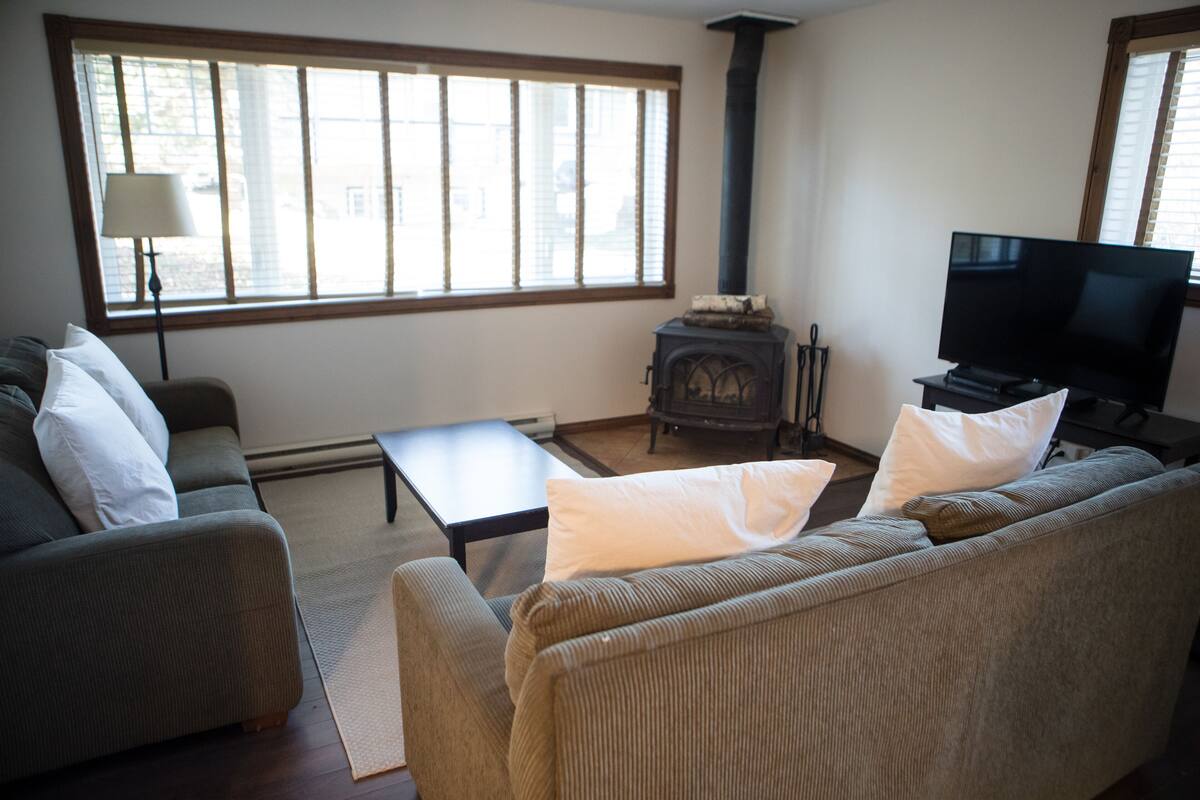Ein Wohnzimmer mit Sofa, Couchtisch, Kamin und Fernseher.