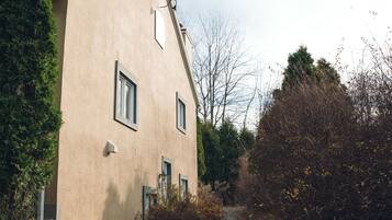 Ein zweistöckiges Gebäude mit sandfarbener Fassade, einem Schornstein und einem Weg zum Eingang.