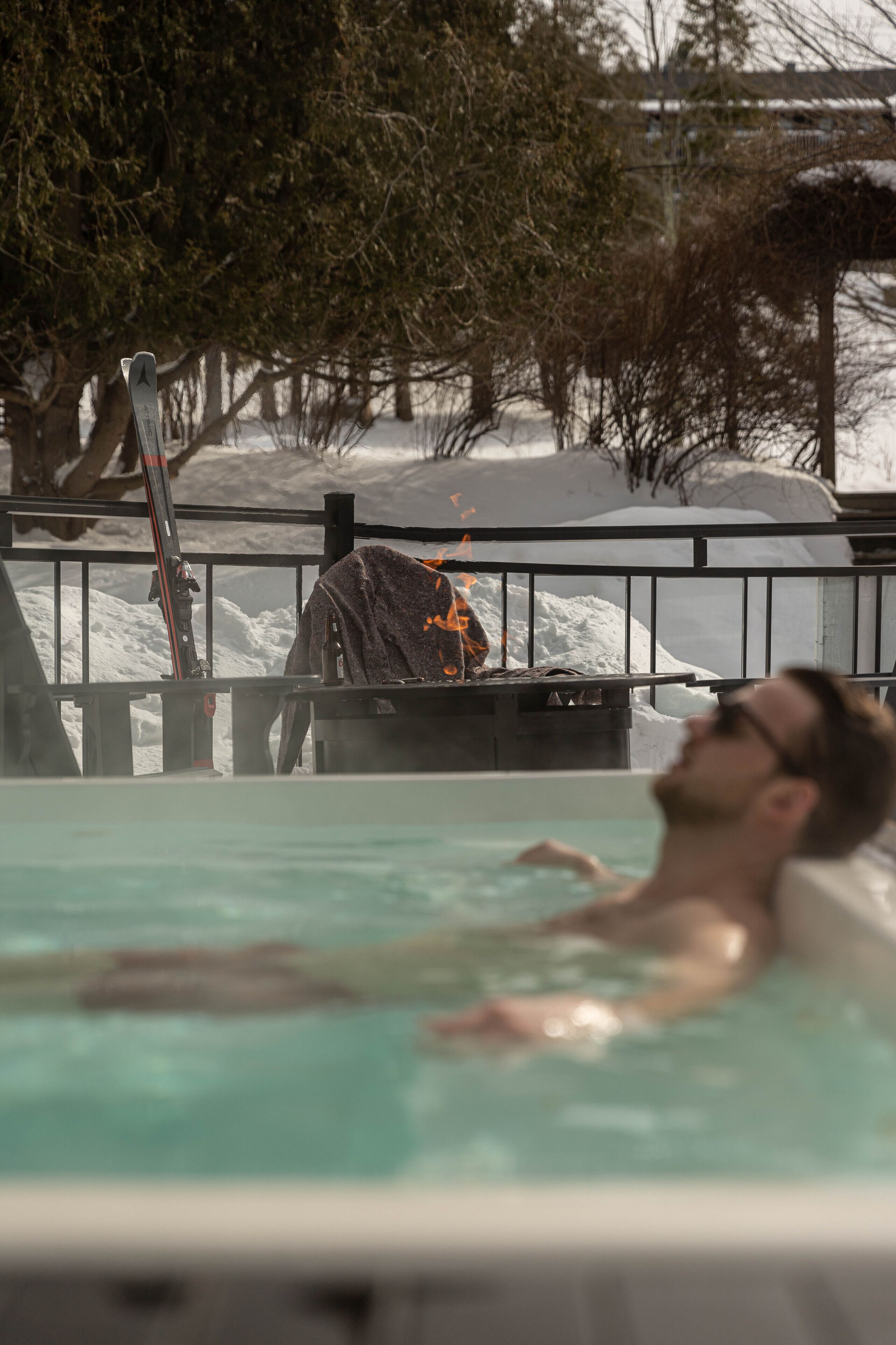A person relaxing in a pool with snow-covered surroundings.