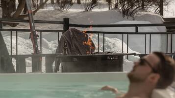 A person relaxing in a pool with snow-covered surroundings.