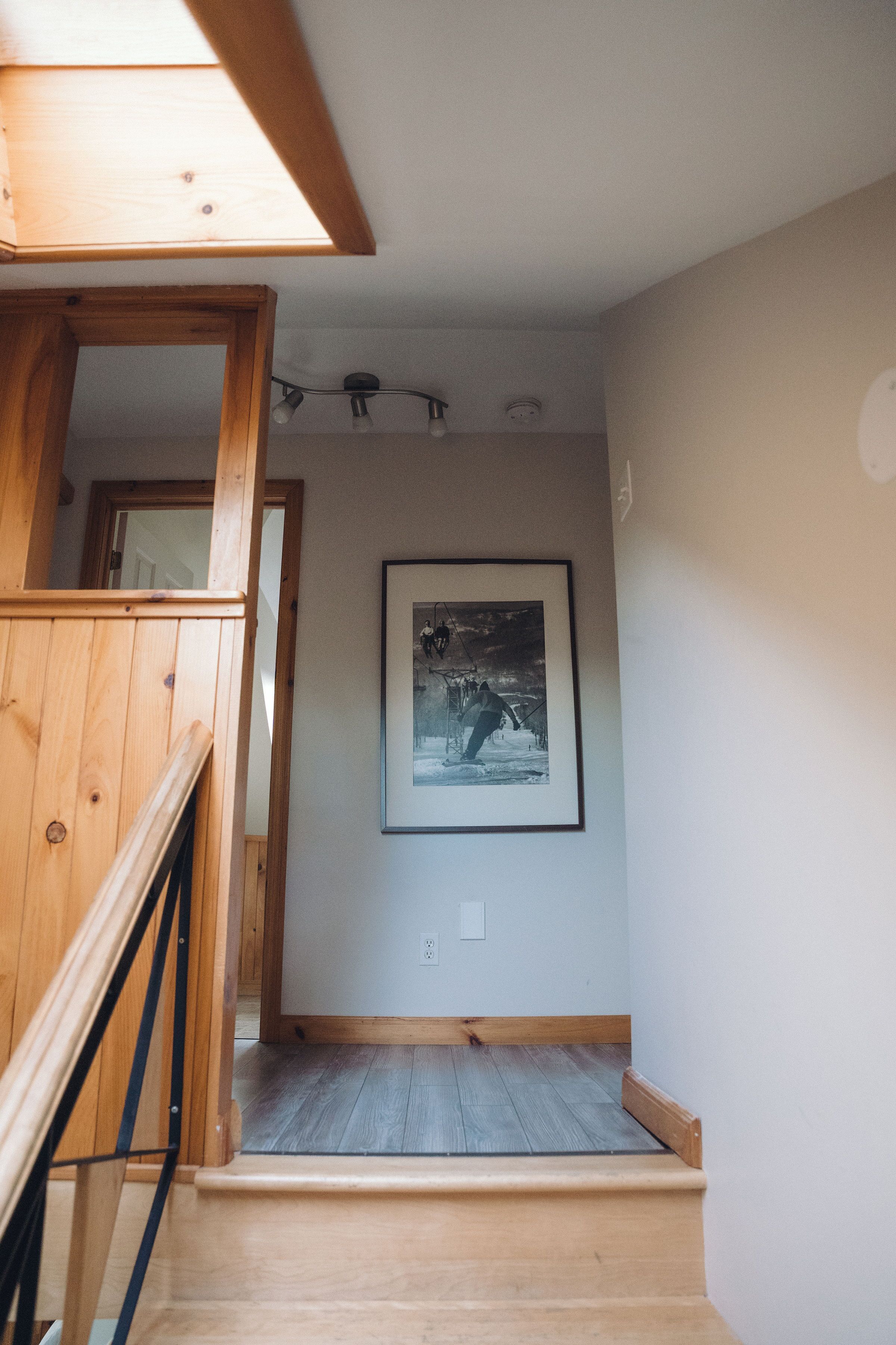 A wooden staircase leading to a room with a framed picture on the wall.