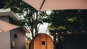 Ett badkar av trä med en bänk och en handduk, omgivet av en pergola och en träkonstruktion.