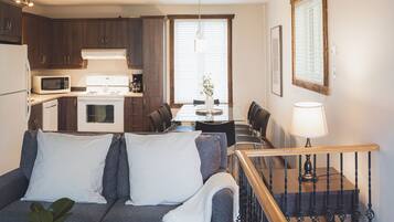 A compact living space with a kitchenette, a dining area, and a staircase.