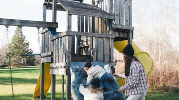 A wooden play structure with a slide and climbing area.